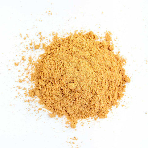 A close-up of fine golden-yellow seasoning powder, spread loosely on a white background, showing a mix of spices optimized for poultry.
