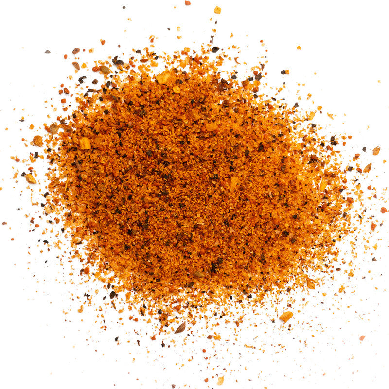 A close-up image of a pile of finely ground orange and black spices, spread out on a white surface.