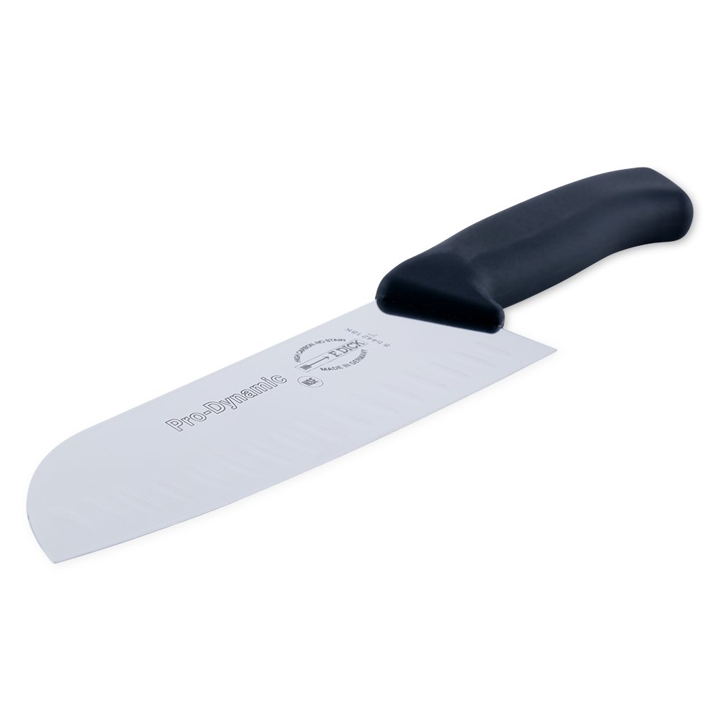 Close-up image of the F. Dick 7" Santoku Kullenschliff - ProDynamic. The knife features a high-carbon stainless steel blade with a kullenschliff edge to prevent food from sticking. It has a black ergonomic handle designed for comfort and control. Displayed on a plain white background, highlighting its sharpness and professional design.