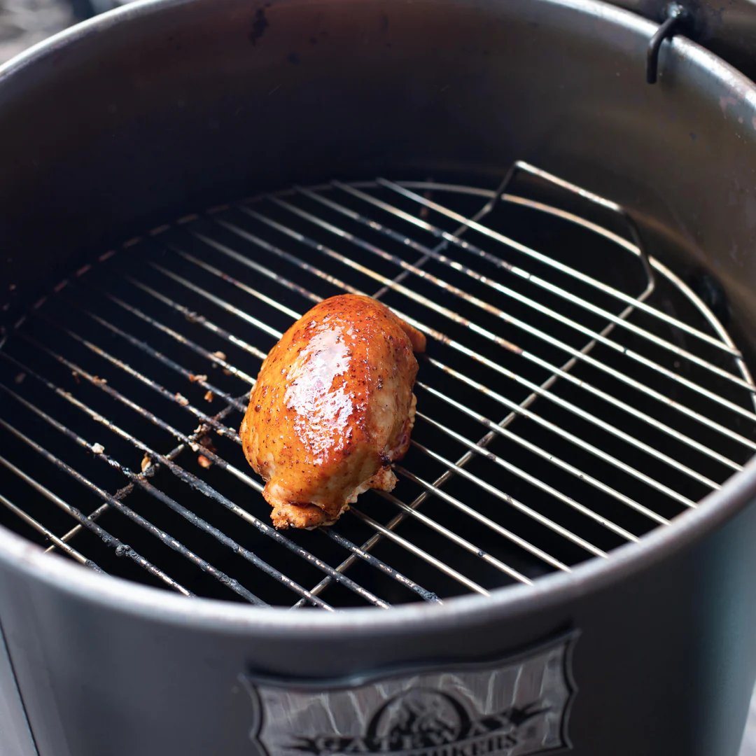 A drum smoker with a cooking grate holding a piece of glazed meat, demonstrating the smoker in use.