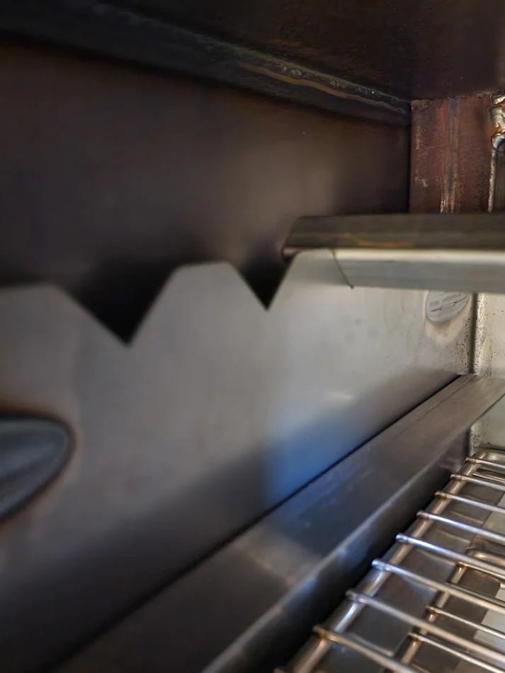 Close-up of the interior of a BBQ smoker, showing the notched brackets used to hold the metal racks in place.