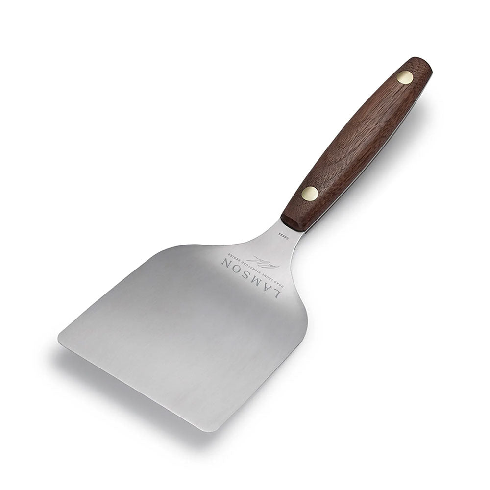 A medium-sized Lamson griddle turner with a stainless steel blade and a wooden handle with two brass rivets. The turner is displayed on a white background, highlighting its smooth finish and robust build.