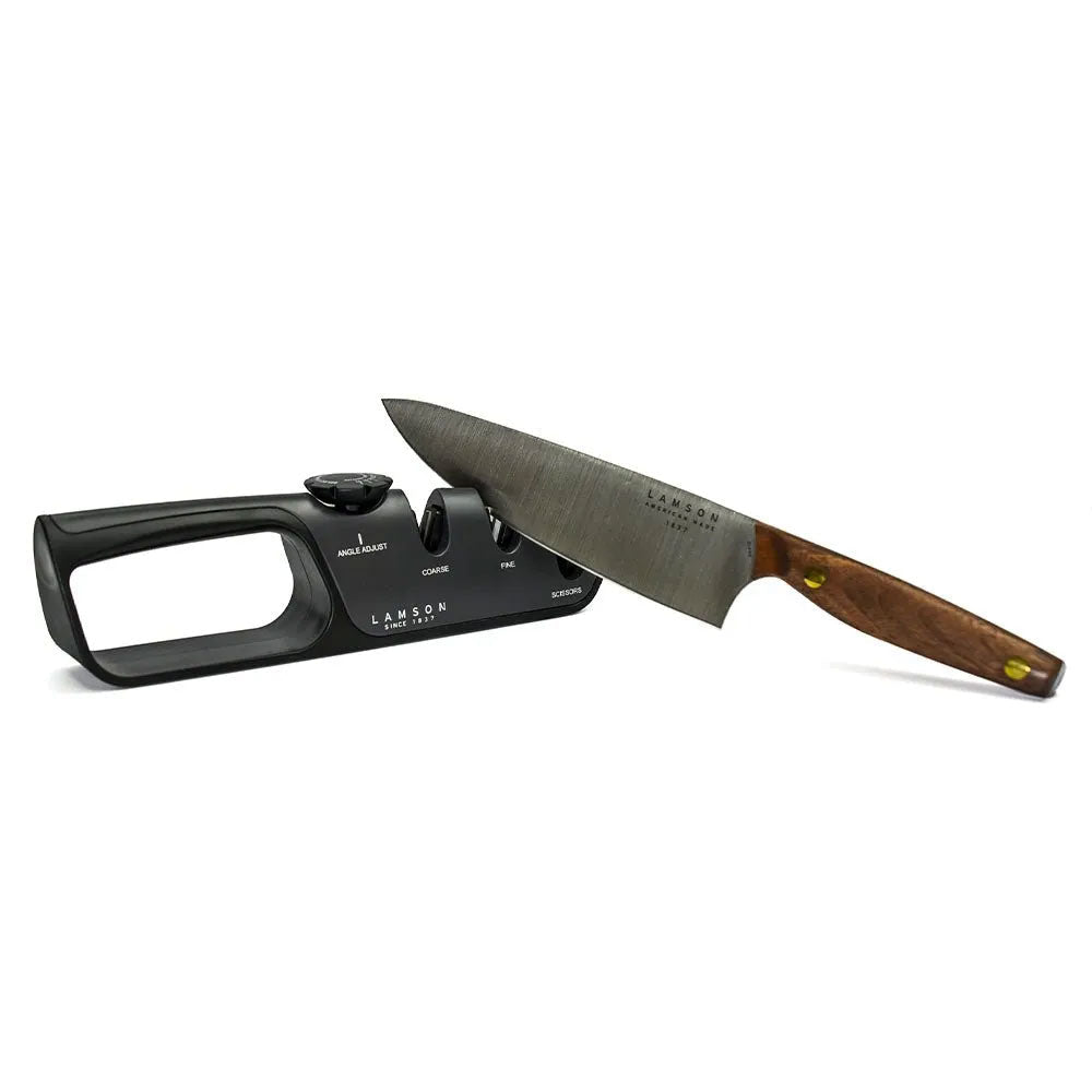 A Lamson adjustable angle knife sharpener with a knife positioned in the coarse slot. The sharpener has a black ergonomic design with labeled slots for angle adjustment, coarse sharpening, fine sharpening, and scissors.