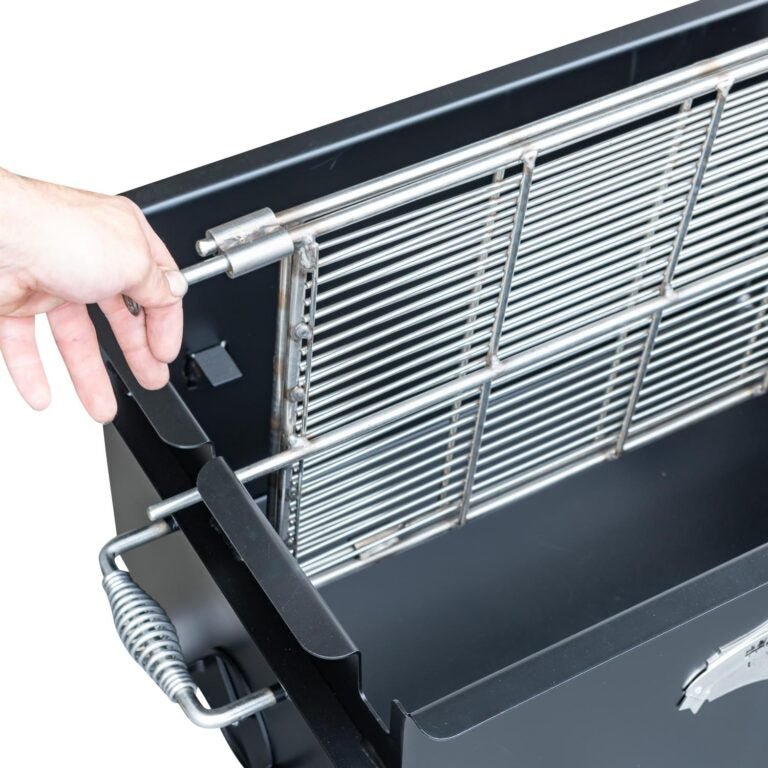 Detail view of the Meadow Creek BBQ26 Chicken Cooker showing a person’s hand lifting the pivoting grate inside the cooker. The grate is designed for easy access and maneuverability.