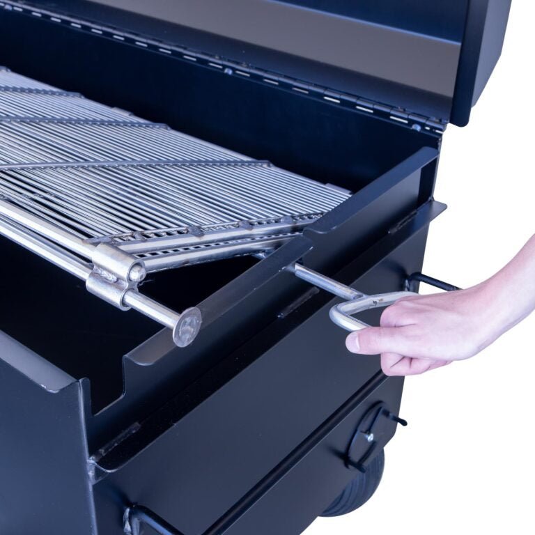 Detail view of the Meadow Creek BBQ42 Chicken Cooker showing a person’s hand lifting the pivoting grate inside the cooker. The grate is designed for easy maneuverability.