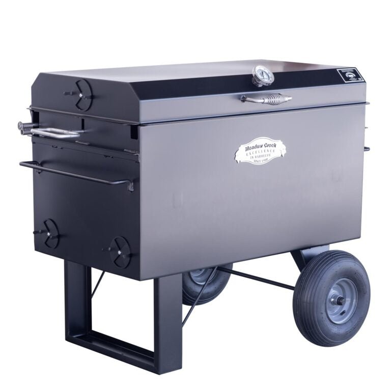 Angled view of the Meadow Creek BBQ42 Chicken Cooker with the lid closed. The cooker has a temperature gauge on the lid and a robust design with large tires for easy transport.