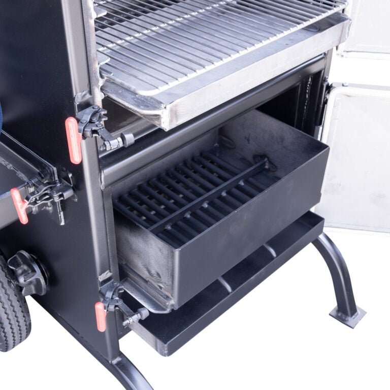 Close-up of the lower compartment of the Meadow Creek BX25 Box Smoker, showing the charcoal basket and ash pan with a stainless steel grate above.