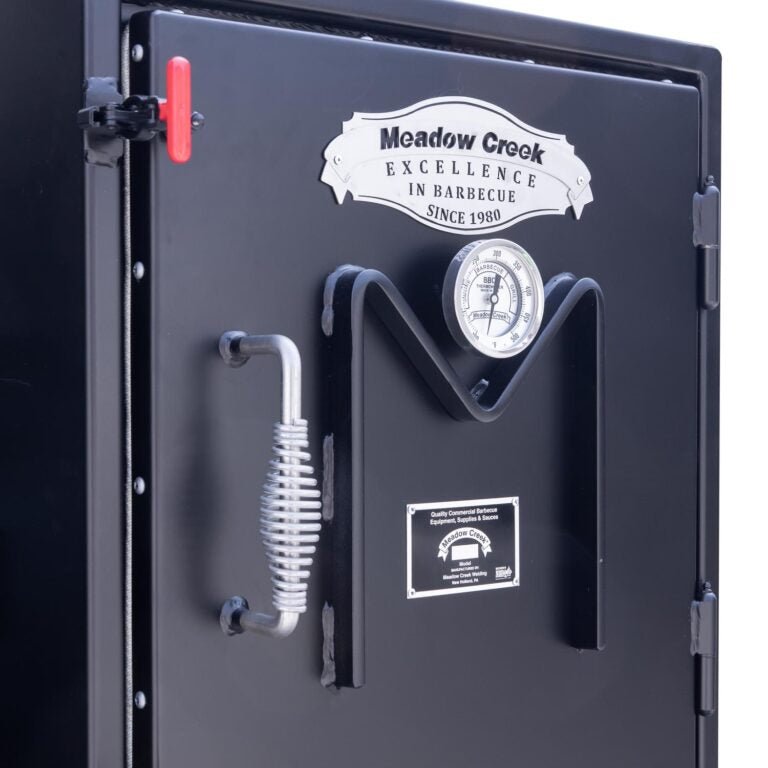 Close-up of the Meadow Creek BX25 Box Smoker's upper compartment door, featuring the brand's logo, thermometer, and a coiled handle.