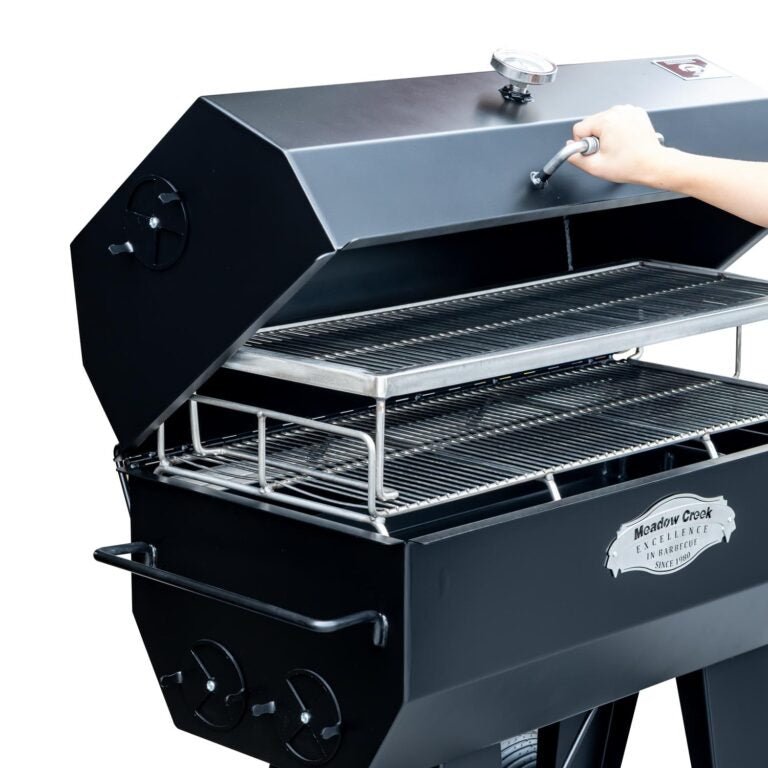 A side view of the Meadow Creek PR36 pig roaster with the upper rack being lifted by a person, demonstrating the ease of use and accessibility of the grill.