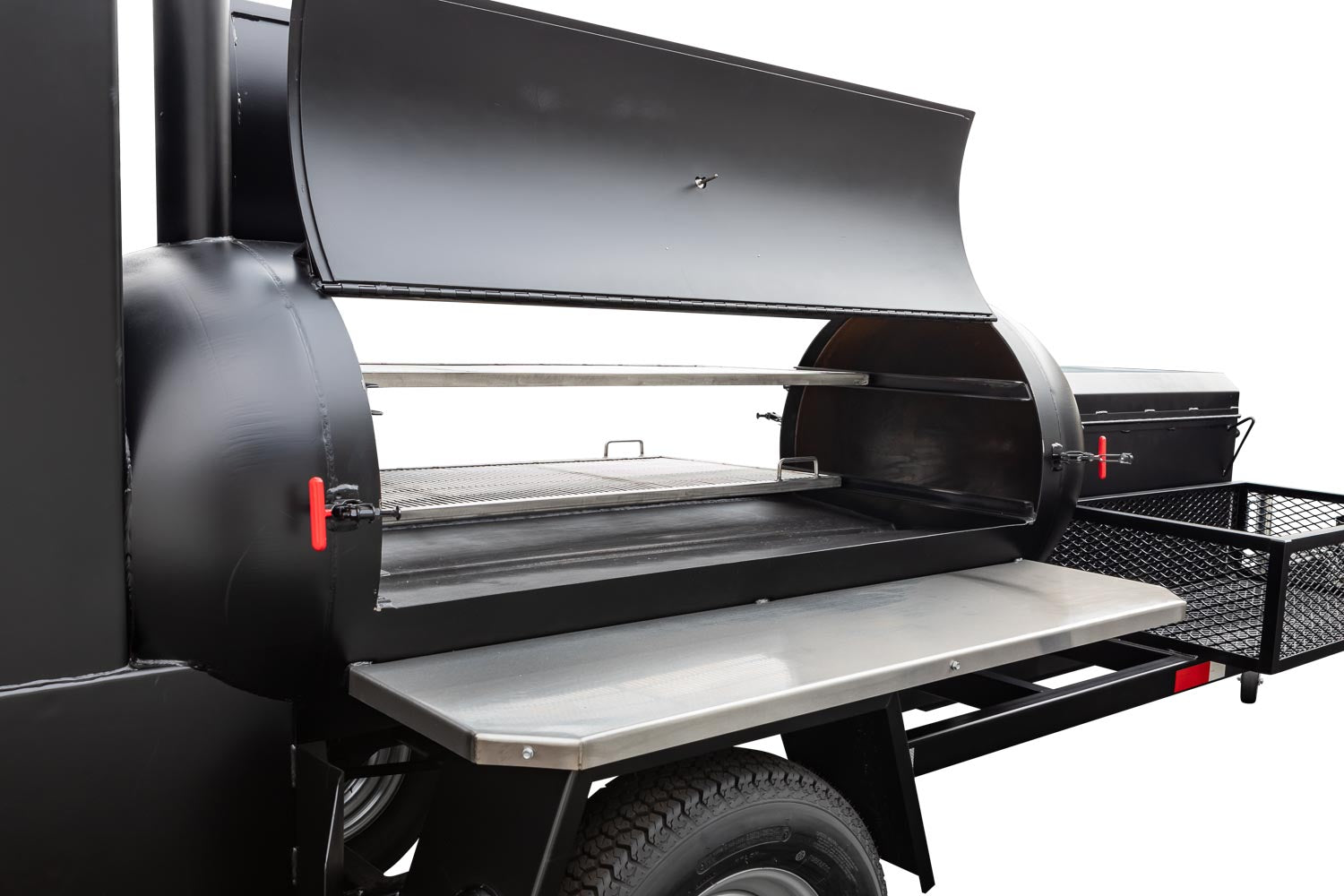 Open view of a large Meadow Creek BBQ smoker trailer with dual grilling racks, stainless steel prep shelf, and red latch handles on a black body.