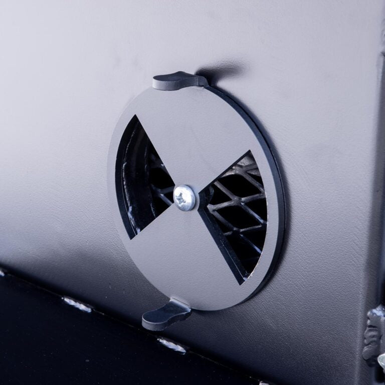 Close-up of the round vent on the side of a black BBQ smoker, designed for airflow control.