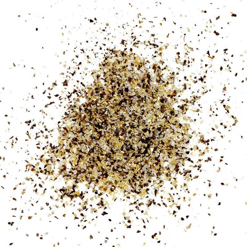 A close-up view of a pile of Meat Church Blanco Steak & Everything Else Seasoning. The seasoning consists of coarse granules with a mix of black, white, and yellowish-brown colors.