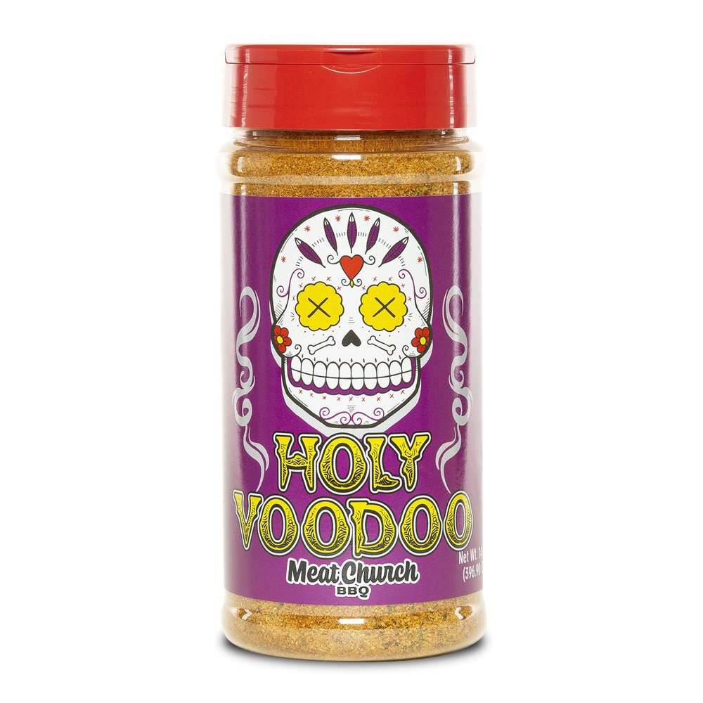 A 14-ounce jar of Meat Church Holy Voodoo Seasoning. The label is purple with yellow text and features a cartoon sugar skull with yellow eyes and a red lid. The jar contains a coarse, orange spice mix.