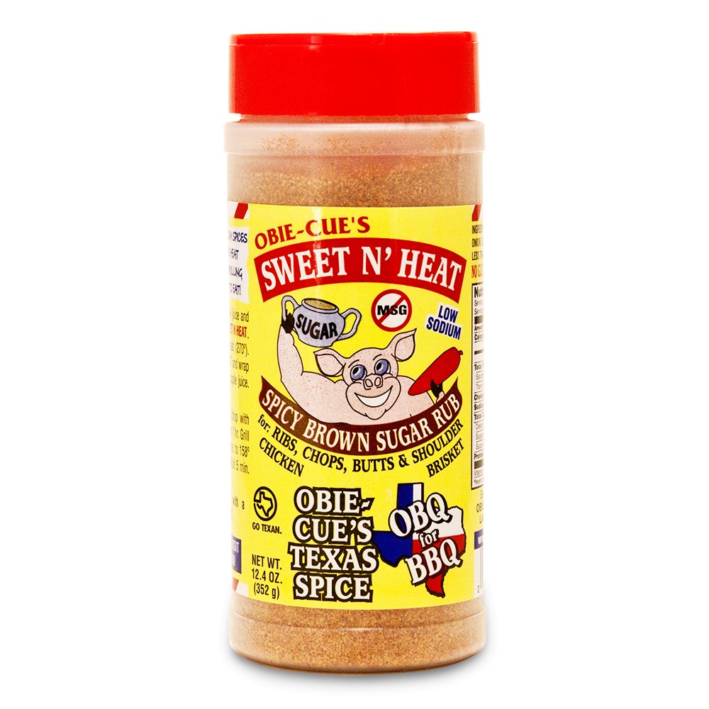 Front view of Obie-Cue's Sweet N' Heat Spicy Brown Sugar Rub bottle. The label features a cartoon pig and highlights the product as a low sodium spicy brown sugar rub for various meats, including ribs and brisket, with added MSG.