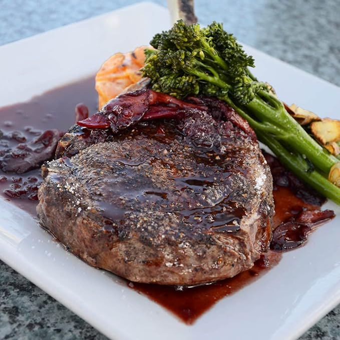 A plated meal featuring a cooked steak topped with Rio Valley Meat Blanco AP Rub seasoning, drizzled with a rich sauce, and accompanied by broccolini and other vegetables.