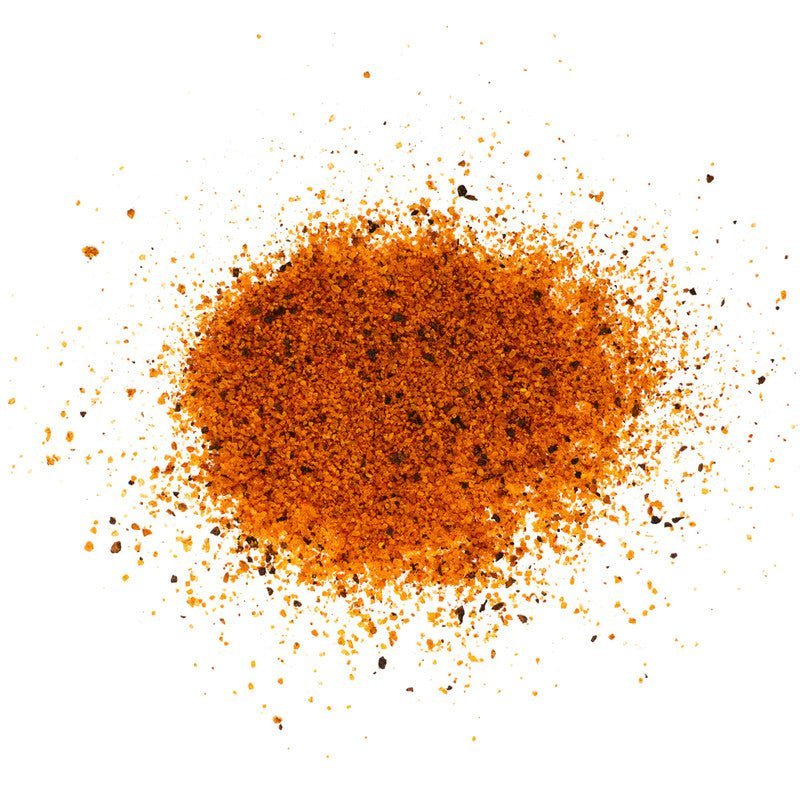 Close-up view of Rio Valley Meat Perfecto Seasoning, showing a pile of reddish-brown seasoning blend with visible coarse grains and spices. The texture appears to be a mix of fine and coarse particles, indicating a rich blend of ingredients.
