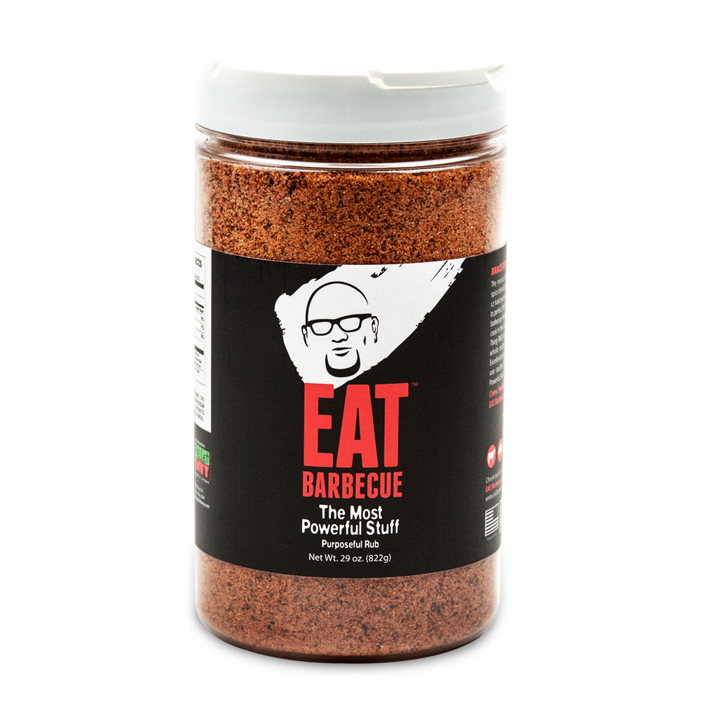 A large plastic jar of EAT Barbecue "The Most Powerful Stuff" BBQ rub, with a white lid and a black label. The label features a white and red logo of a man's face with glasses, and the text "EAT Barbecue" in bold red letters. The jar contains 29 ounces (1 lb 13 oz) of the seasoning.