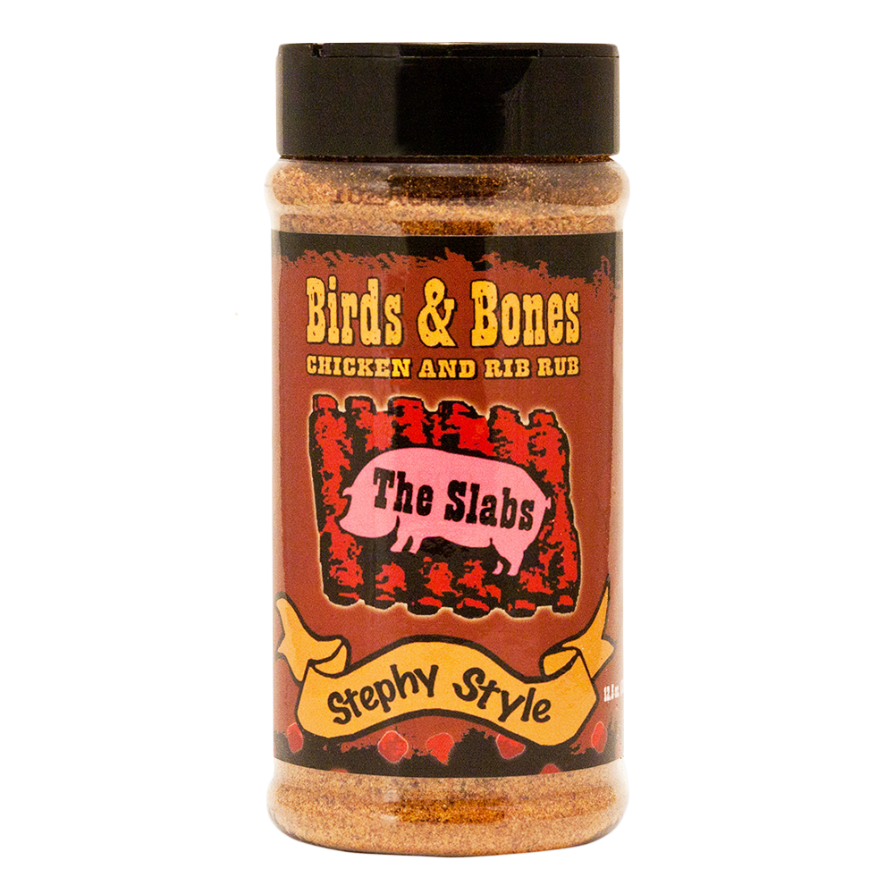  The front of a container of The Slabs Birds & Bones Chicken and Rib Rub, Stephy Style, with a black cap. The label features a rustic design with the product name in bold yellow text and an illustration of a pink pig with the words "The Slabs" on its side. Below the illustration is a yellow ribbon with "Stephy Style" written on it. The container holds 12.5 oz (354g) of seasoning.