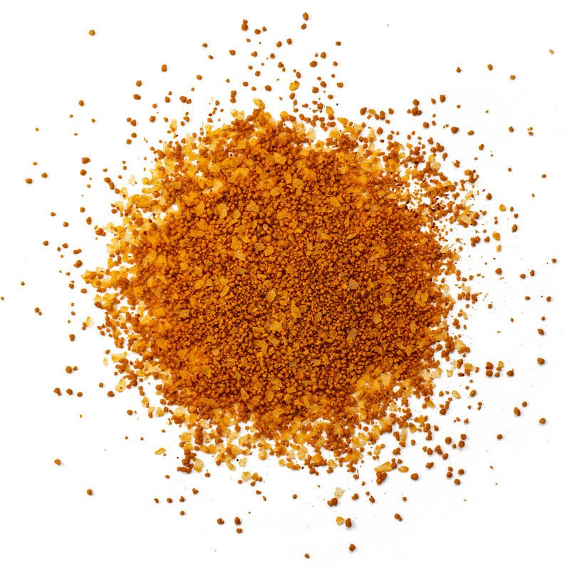 A close-up view of Simply Marvelous The Genie's Hooch Rub, showing a mixture of finely ground orange and brown granules with various spices and seasonings.