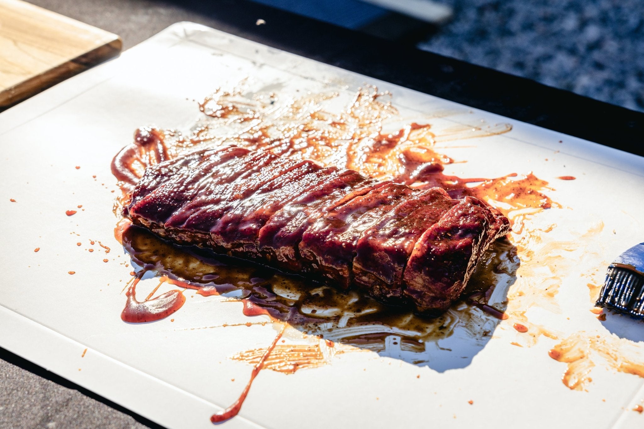 Slab of ribs placed on a disposable cutting board, ready for BBQ preparation.