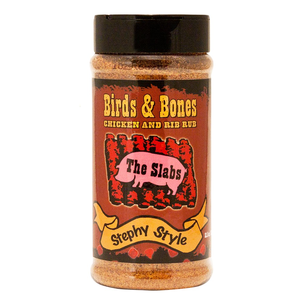  The front of a container of The Slabs Birds & Bones Chicken and Rib Rub, Stephy Style, with a black cap. The label features a rustic design with the product name in bold yellow text and an illustration of a pink pig with the words "The Slabs" on its side. Below the illustration is a yellow ribbon with "Stephy Style" written on it. The container holds 12.5 oz (354g) of seasoning.