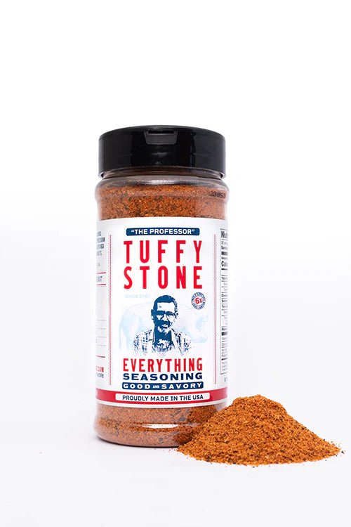 A close-up view of Tuffy Stone Everything Seasoning with the label visible, showing the brand name, a picture of Tuffy Stone, and the product description. A small pile of the seasoning is placed in front of the bottle.