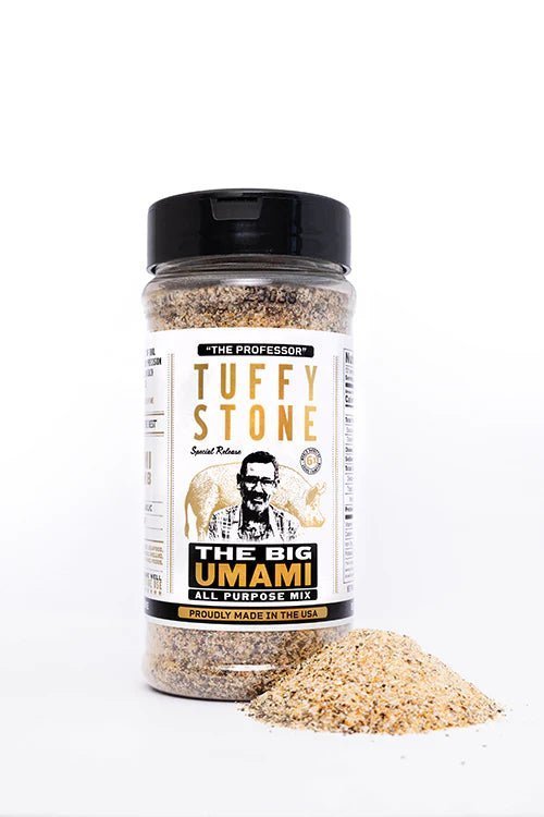 A plastic bottle of Tuffy Stone The Big Umami All Purpose Mix with a black lid, next to a small pile of the mix on a white surface. The label shows Tuffy Stone, 'The Professor,' and the product name in gold and black text.